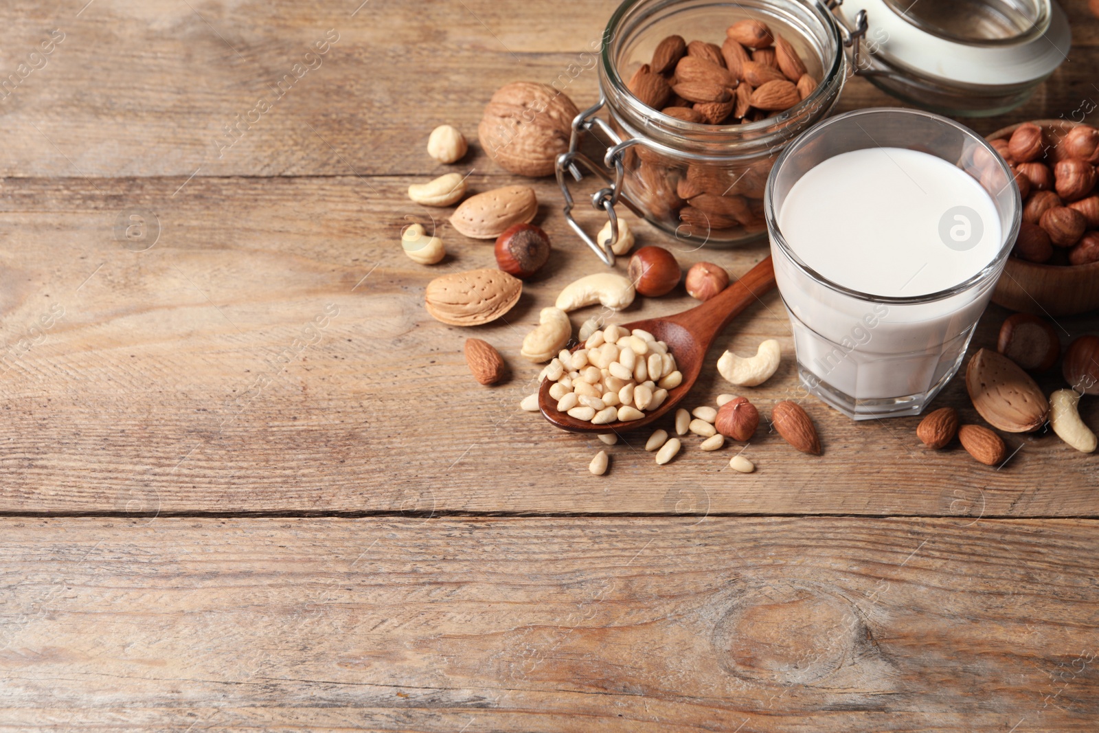 Photo of Vegan milk and different nuts on wooden table. Space for text