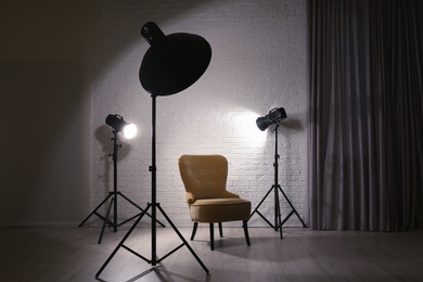 Photo of Interior of modern photo studio with professional lighting equipment and armchair