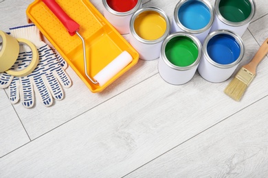 Photo of Cans of paint and decorator tools on wooden floor. Space for text