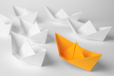 Photo of Orange paper boat among others on white background, closeup. Leadership concept