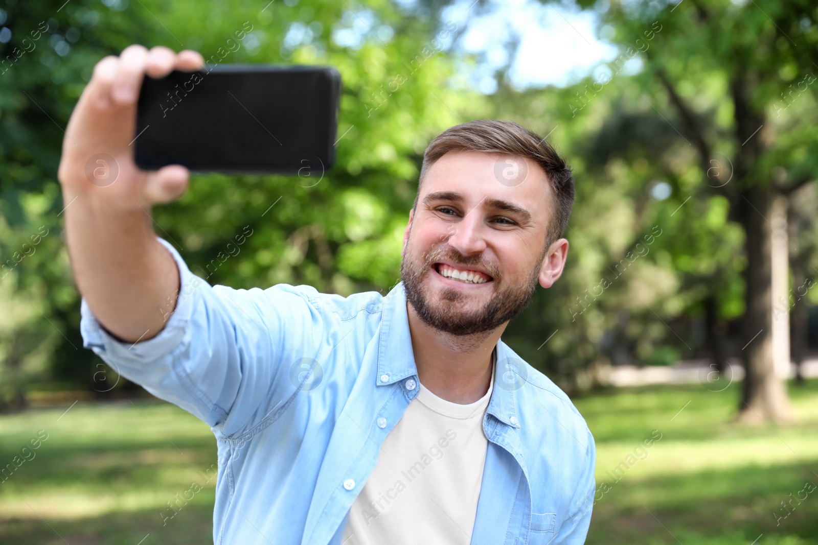 Photo of Happy young man taking selfie in park