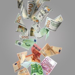 Image of Money exchange. Many dollars and euro banknotes falling on grey background