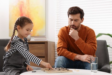 Father playing checkers with his daughter at home