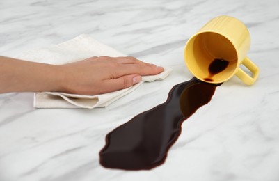 Woman cleaning spilled coffee on white marble table, closeup