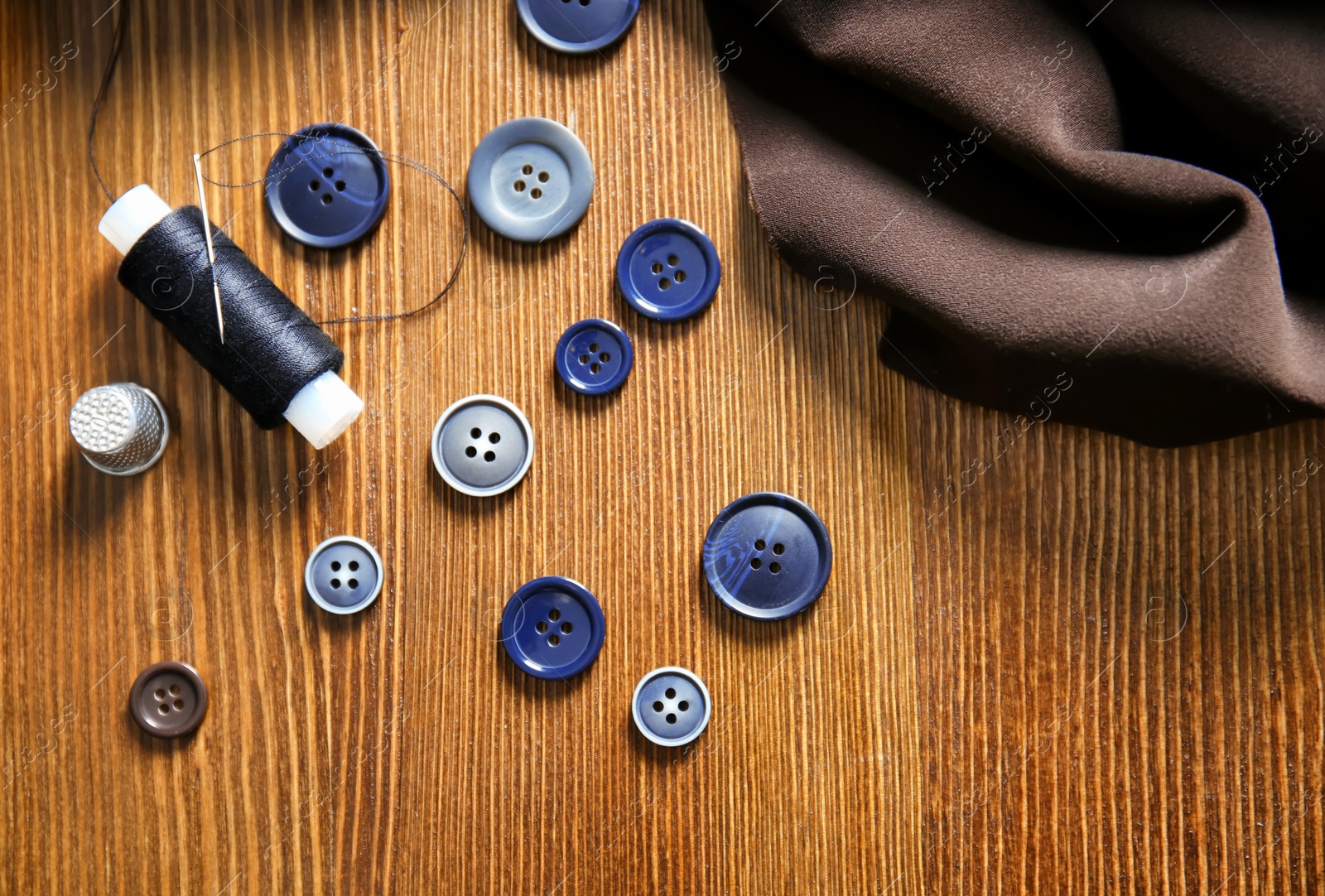 Photo of Thread, fabric and buttons for tailoring on wooden background