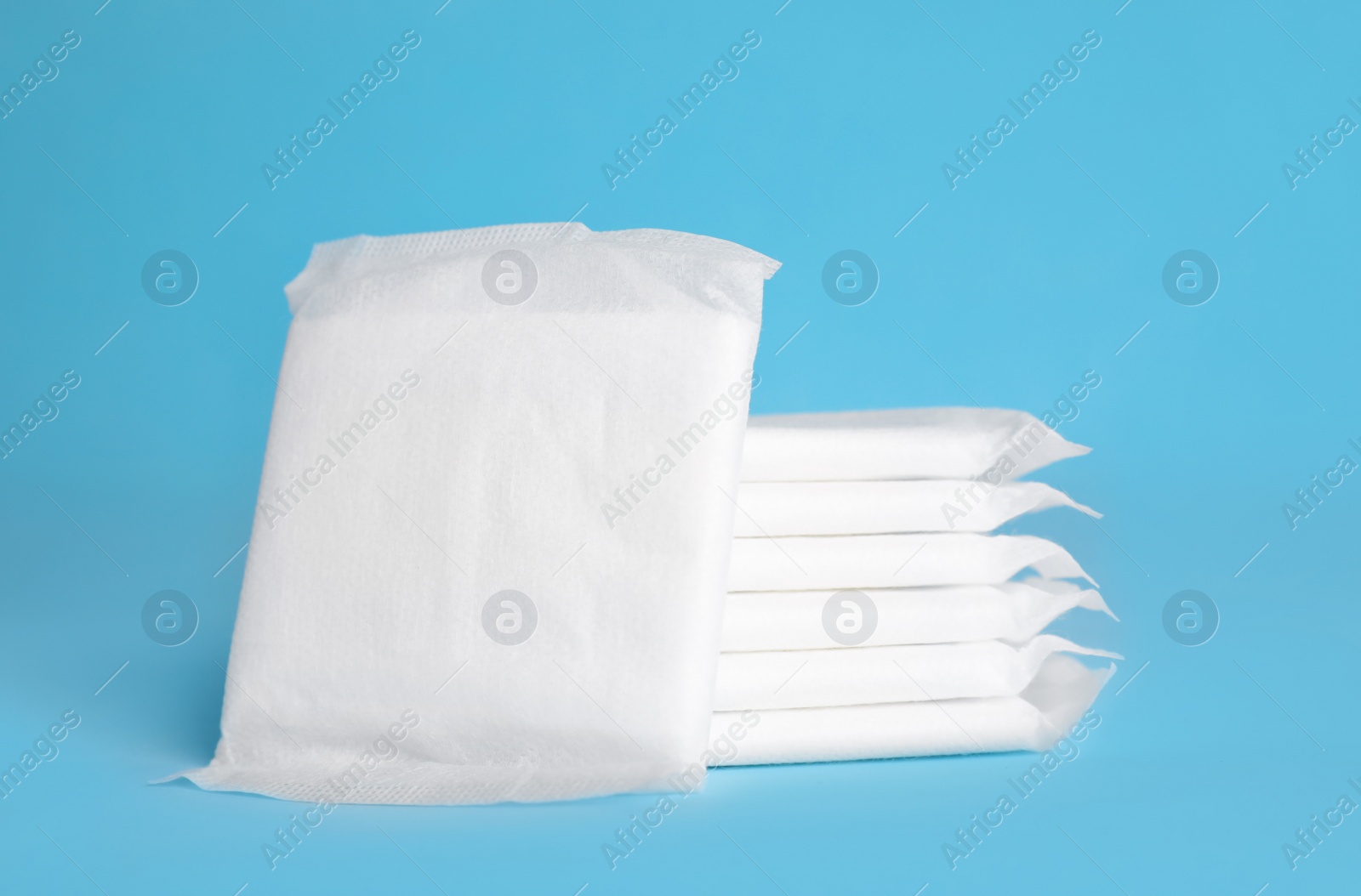 Photo of Stack of menstrual pads on light blue background