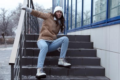 Photo of Young woman fallen on slippery stairs covered with ice outdoors