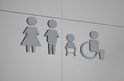 Grey public toilet sign on light wall