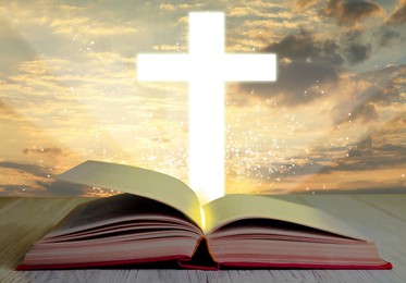 Image of Silhouette of cross and open Bible on white wooden table at sunrise