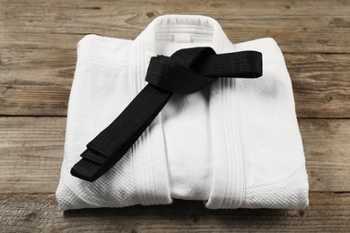 Photo of Black karate belt and white kimono on wooden background