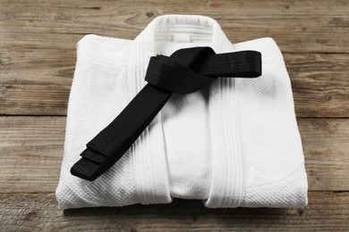 Black karate belt and white kimono on wooden background