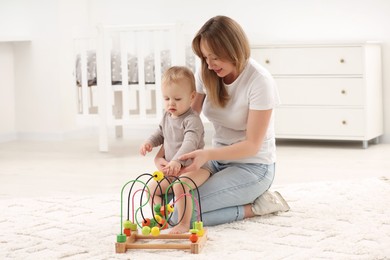 Photo of Children toys. Mother and her little son playing with bead maze on rug at home