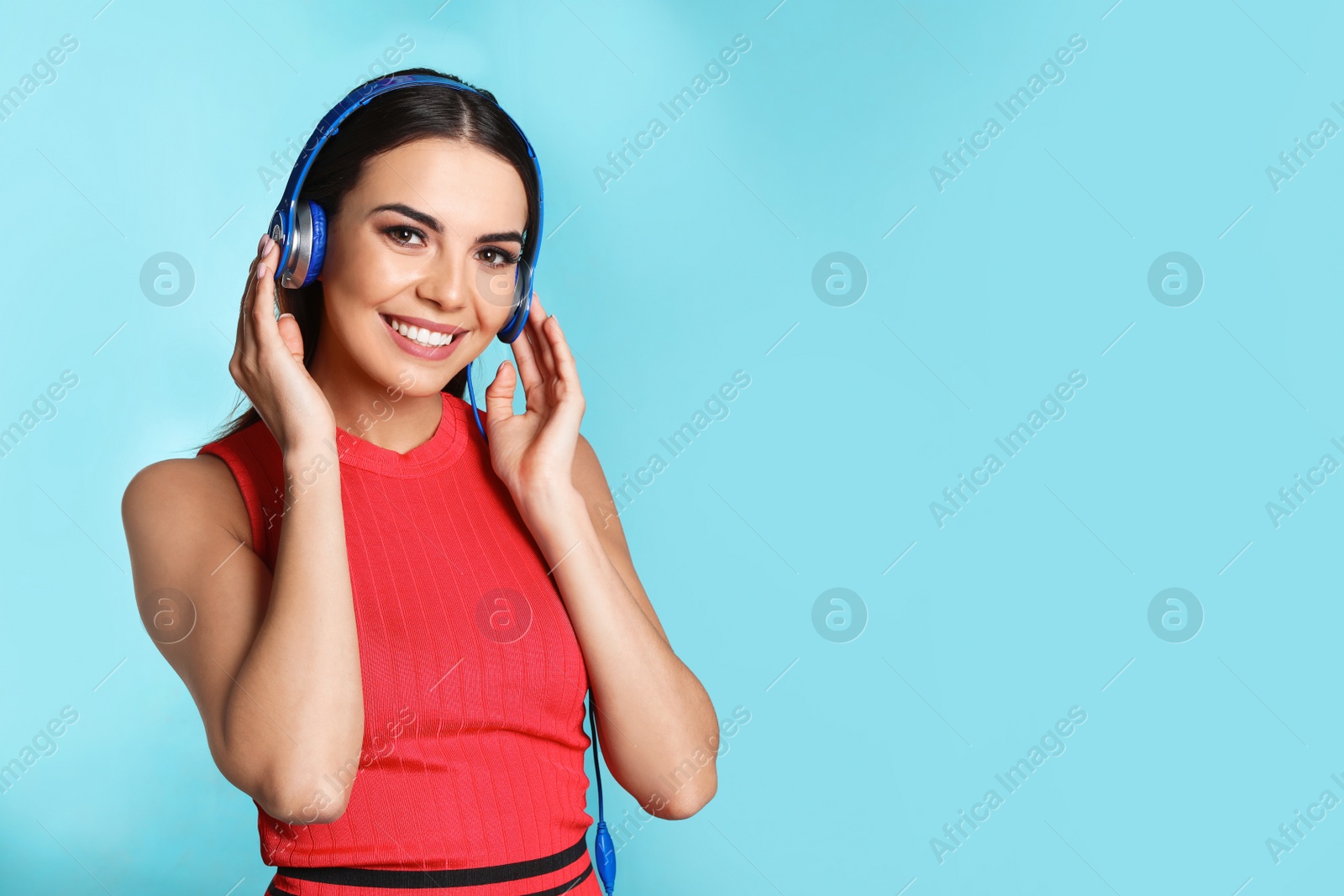 Photo of Attractive young woman enjoying music in headphones on color background. Space for text