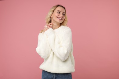 Photo of Happy woman in stylish warm sweater on pink background