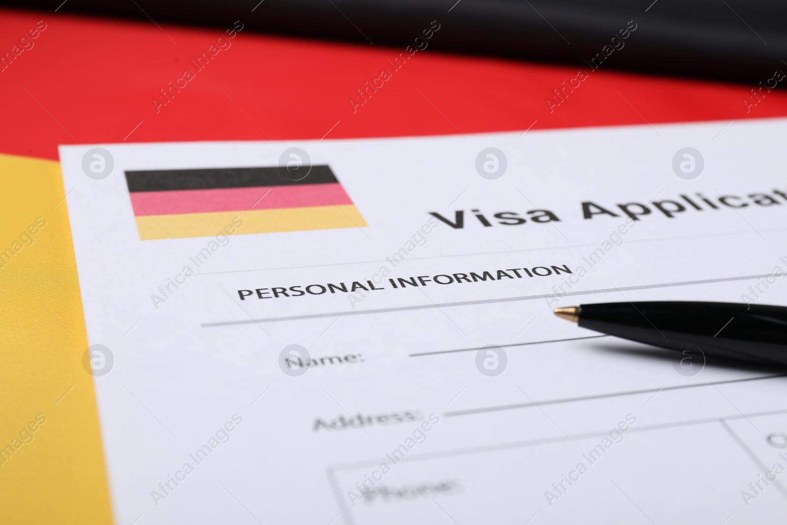 Photo of Immigration to Germany. Visa application form and pen on flag, closeup