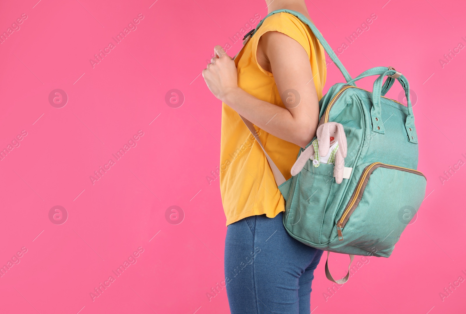 Photo of Woman with maternity backpack for baby accessories on color background, closeup. Space for text