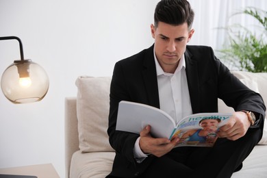 Man reading magazine on sofa in office