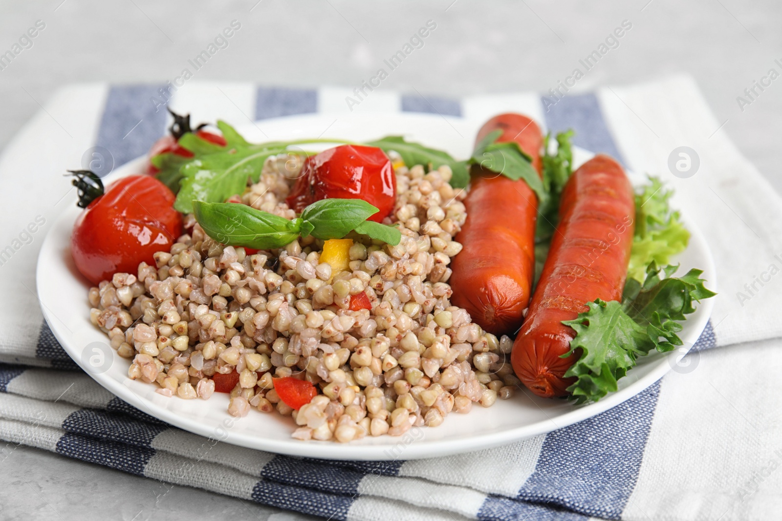 Photo of Tasty buckwheat porridge with sausages on table, closeup