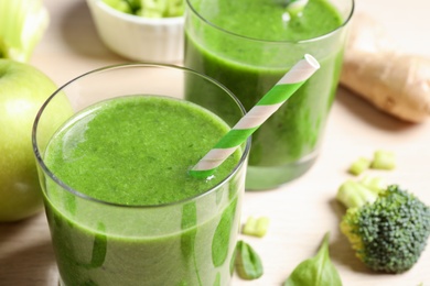 Delicious fresh green juice with straw in glass, closeup