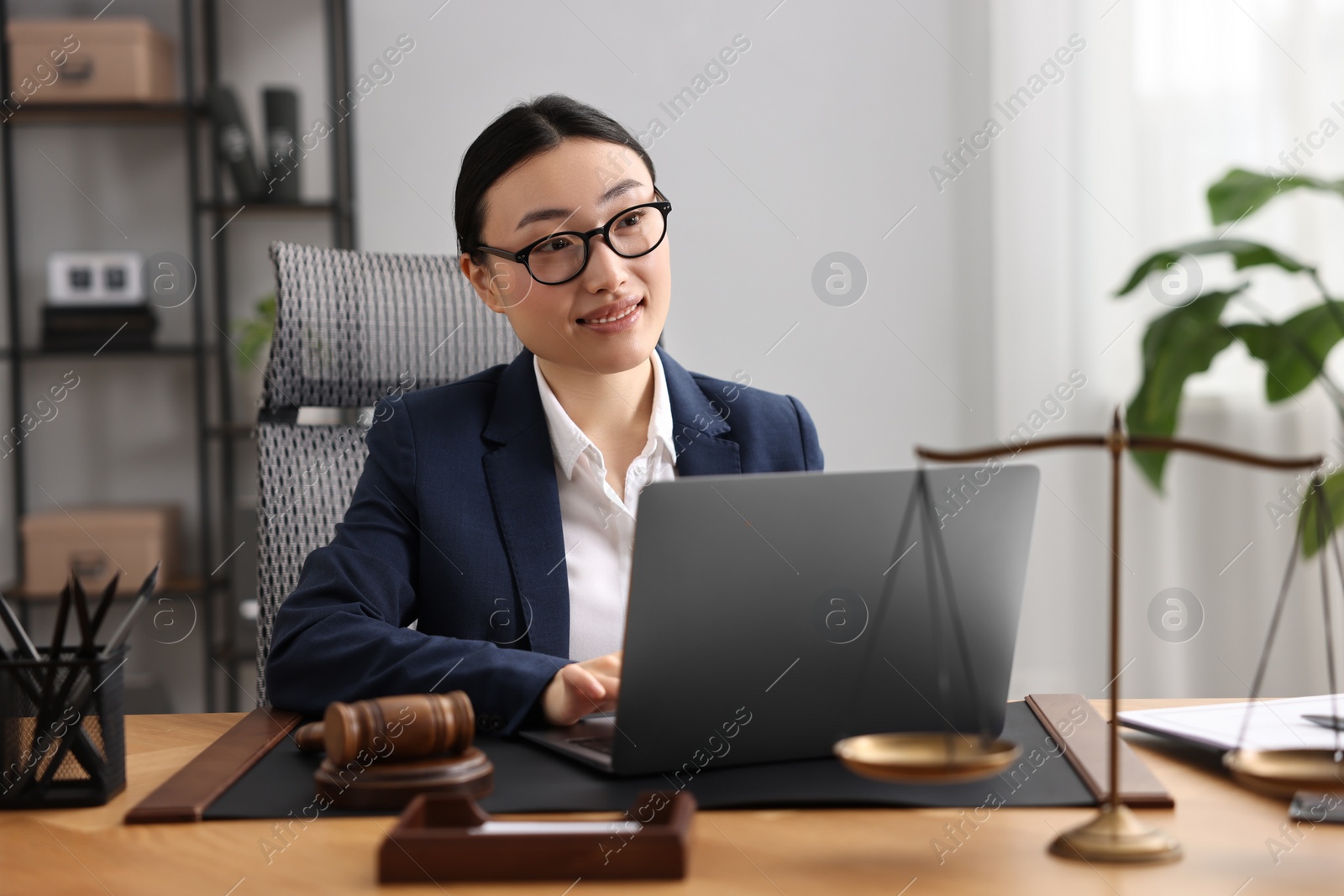 Photo of Smiling notary working with laptop at table in office