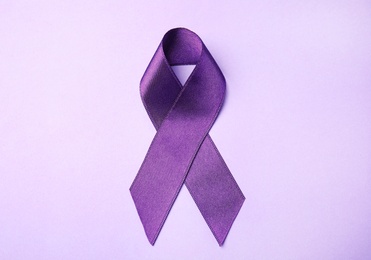 Purple ribbon on lilac background, top view. Domestic violence awareness