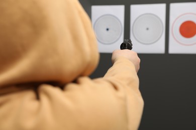 Man aiming at shooting target indoors, selective focus