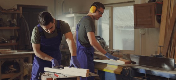 Professional carpenters working with wood in shop. Banner design