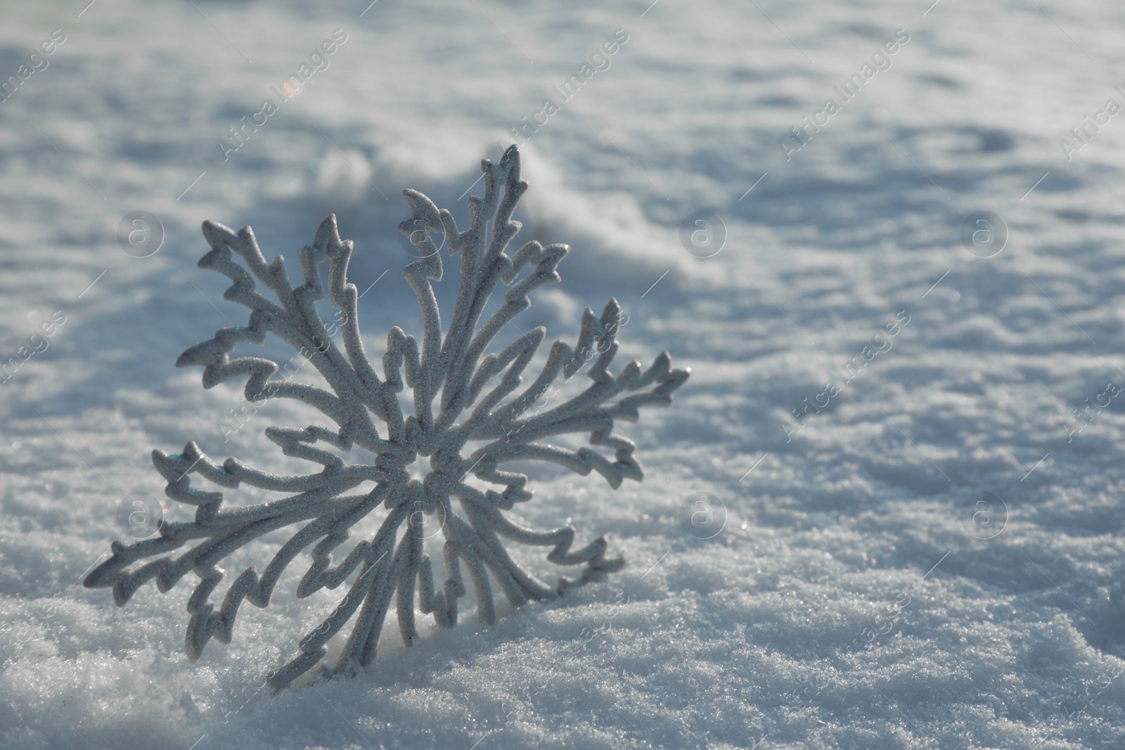 Photo of Beautiful decorative snowflake in white snow, outdoors. Space for text