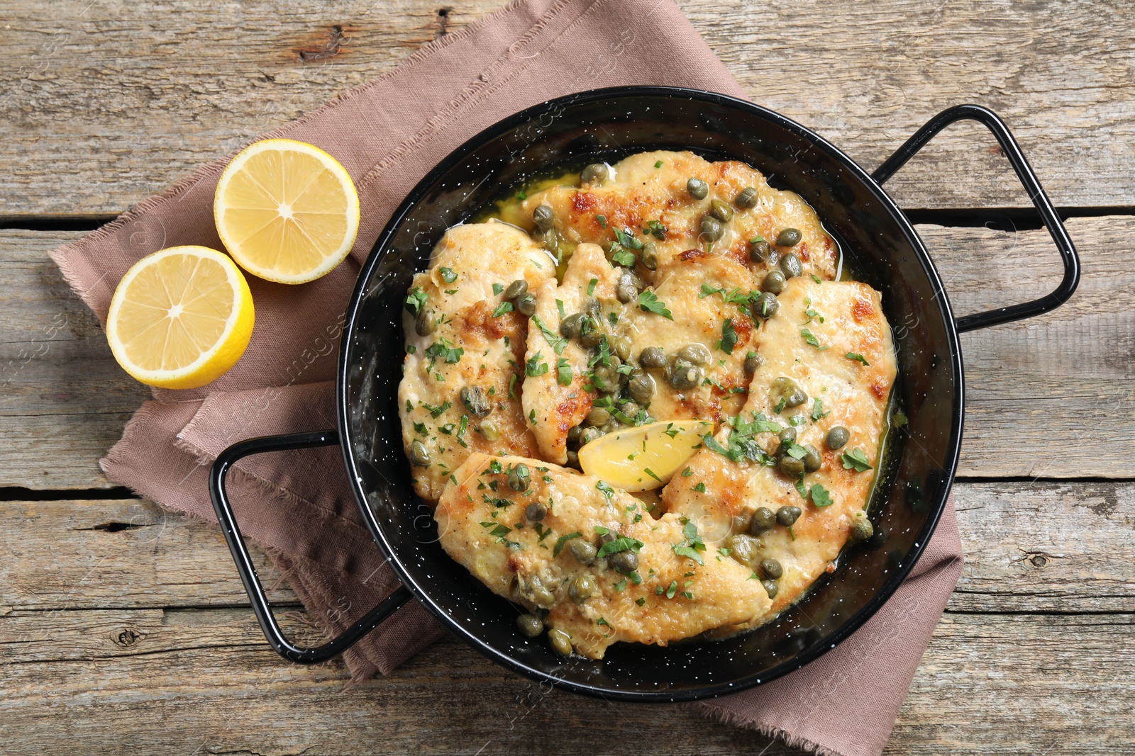 Photo of Delicious chicken piccata with herbs and lemon on wooden table, flat lay