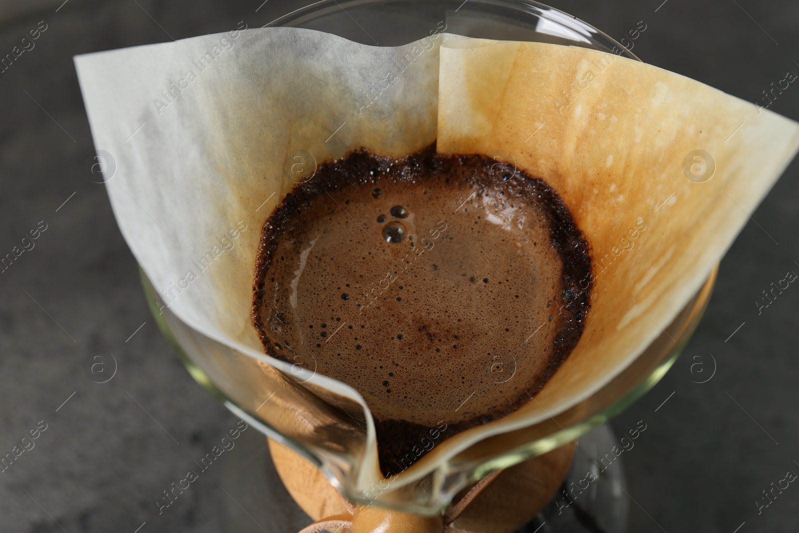 Photo of Paper filter with aromatic drip coffee in glass chemex coffeemaker, closeup