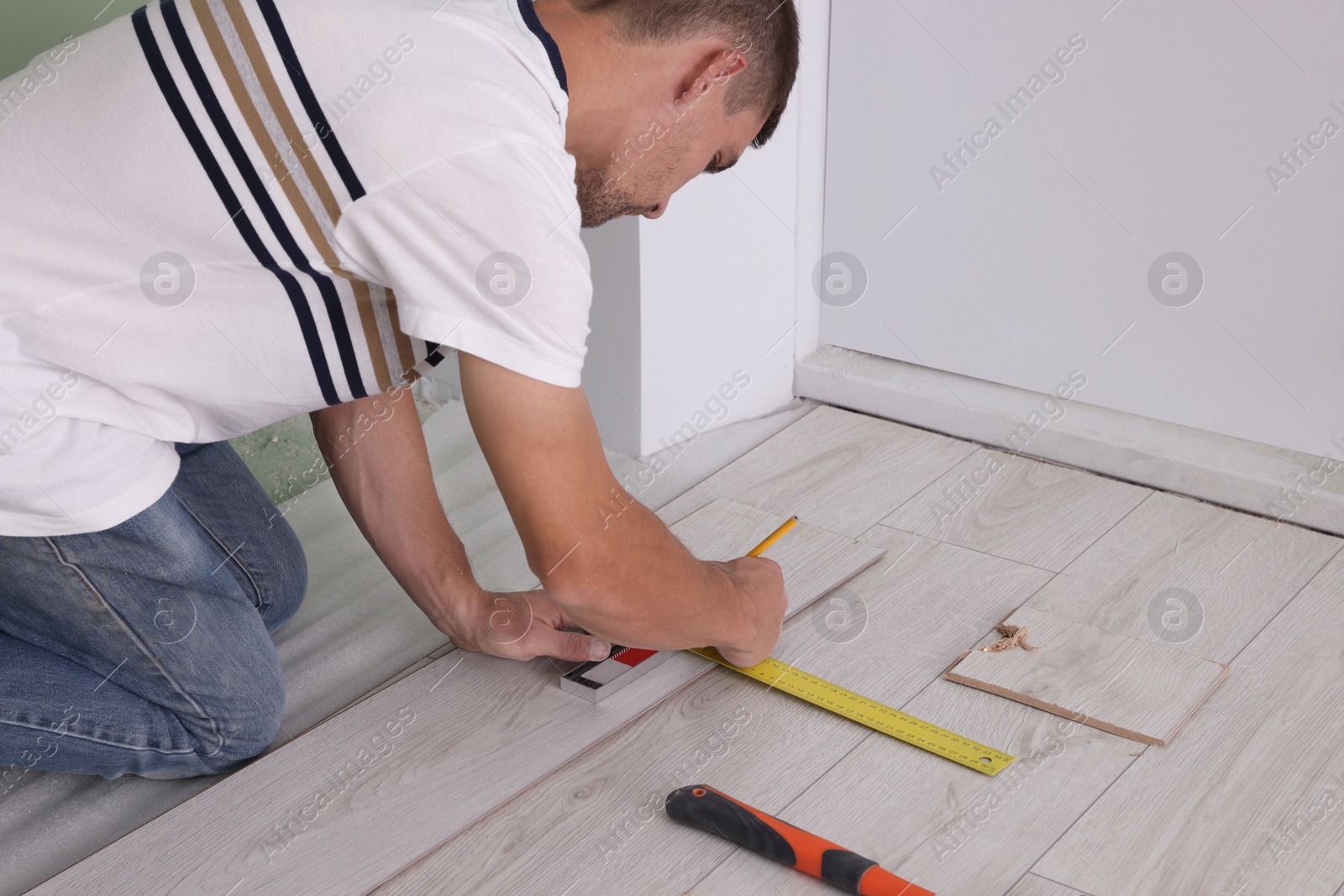 Photo of Man using measuring tape during installation of laminate flooring, closeup