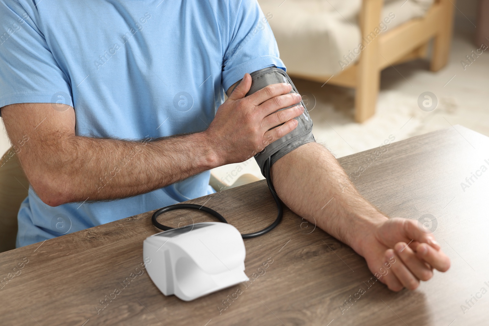 Photo of Man measuring blood pressure at table indoors, closeup