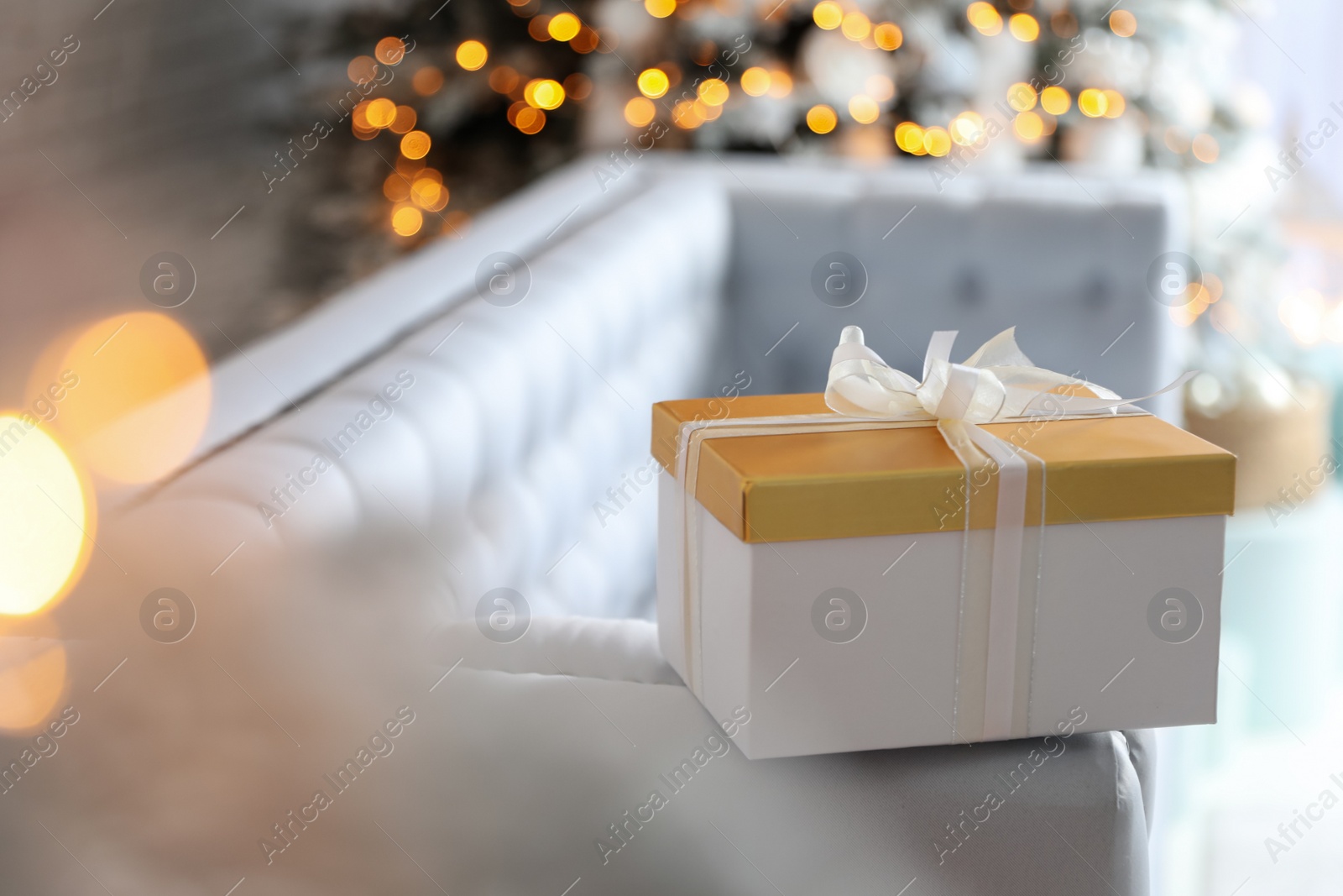 Photo of Christmas gift box on sofa in festive interior