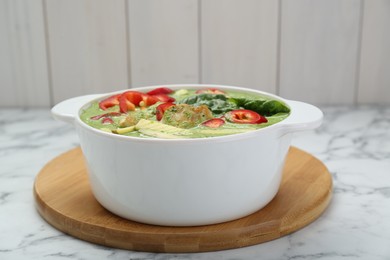 Photo of Saucepan with delicious green curry chicken soup on white marble table