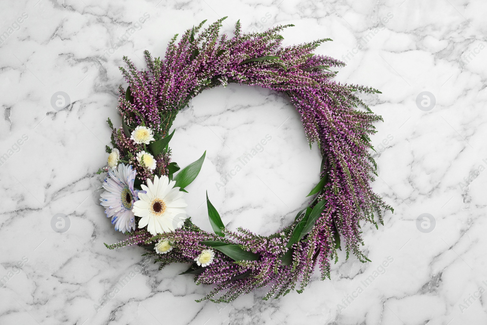 Photo of Beautiful autumnal wreath with heather flowers on white marble background, top view. Space for text