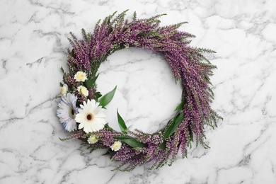 Photo of Beautiful autumnal wreath with heather flowers on white marble background, top view. Space for text