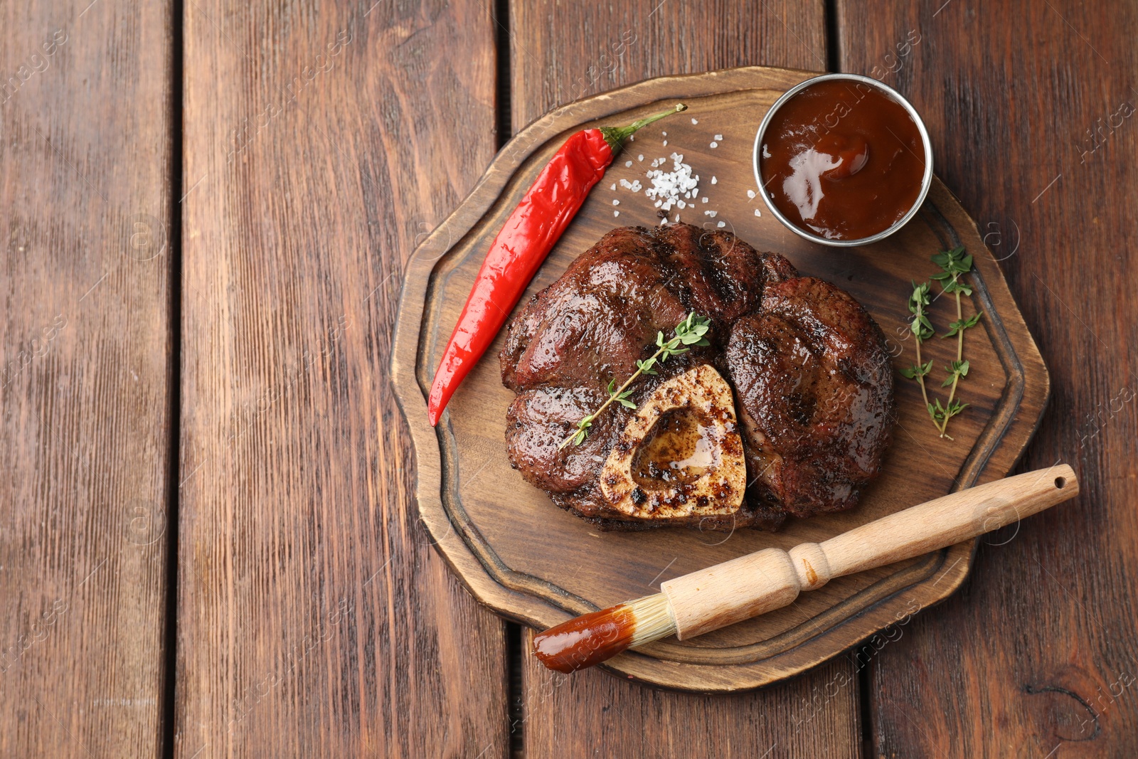 Photo of Delicious roasted beef meat served with sauce and spices on wooden table, top view. Space for text