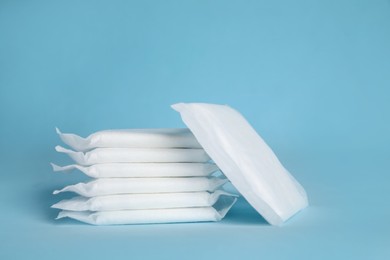 Photo of Stack of menstrual pads on light blue background