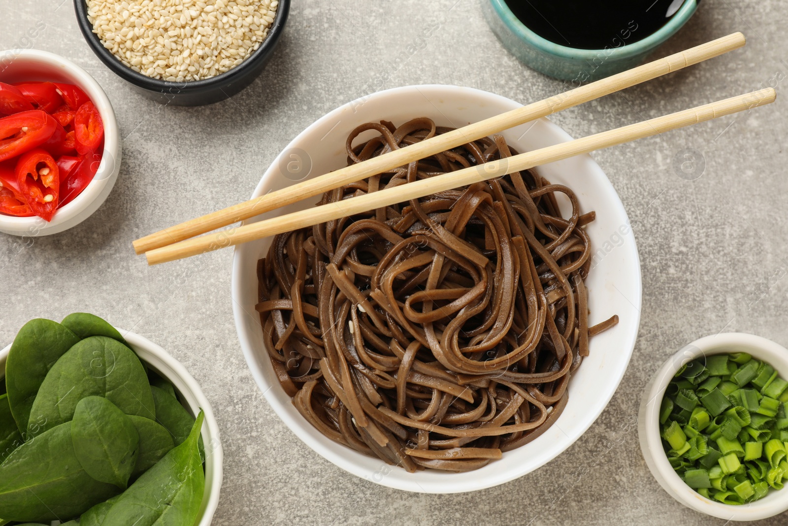 Photo of Tasty buckwheat noodles (soba) served on light grey table, flat lay