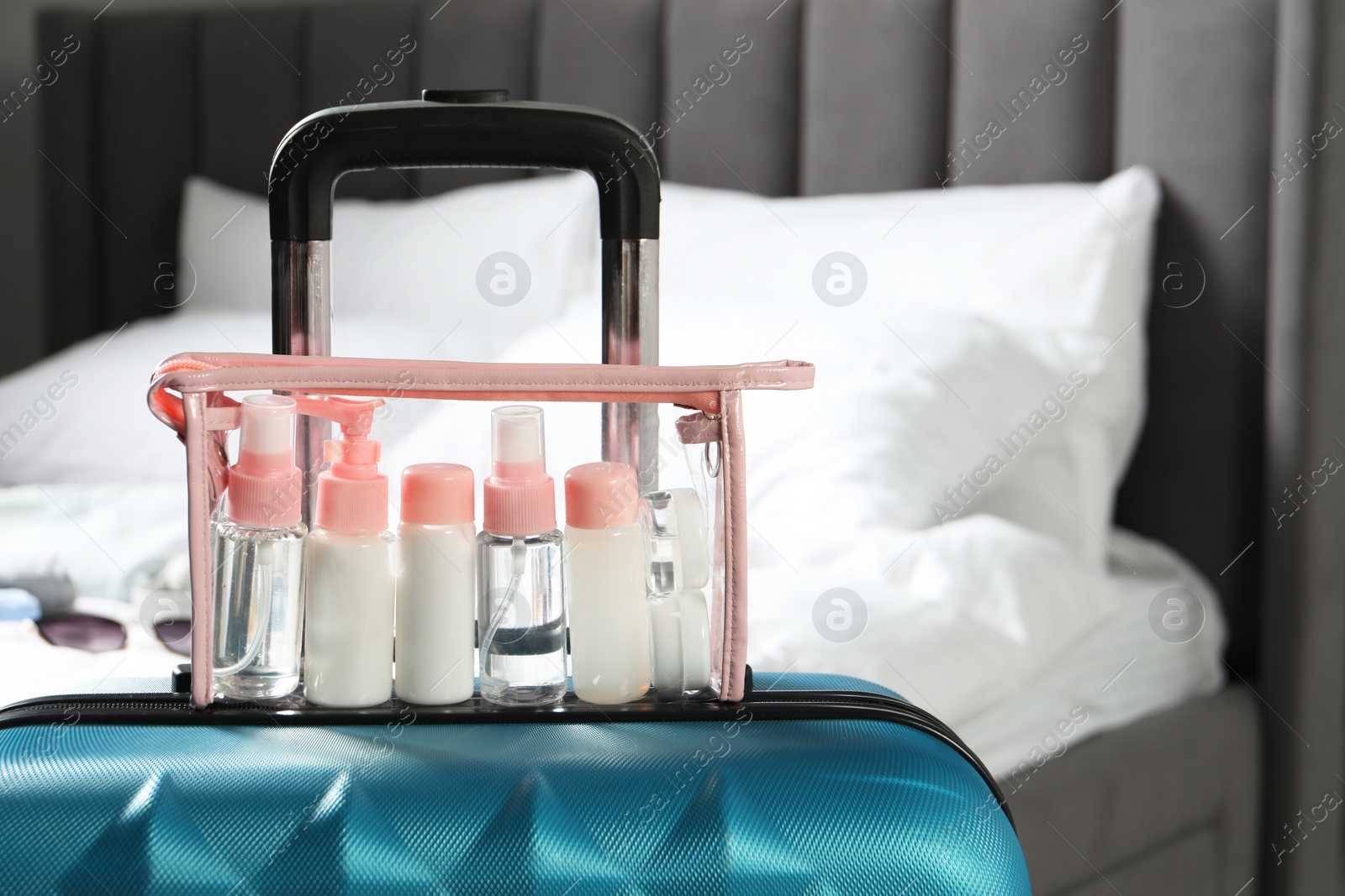 Photo of Cosmetic travel kit. Plastic bag with small containers of personal care products on suitcase in bedroom, space for text