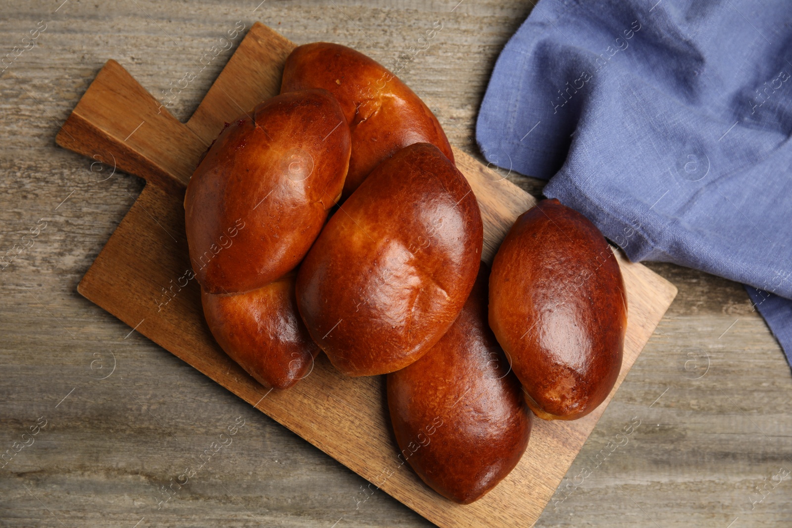 Photo of Delicious baked pirozhki on wooden table, flat lay