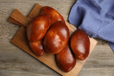 Photo of Delicious baked pirozhki on wooden table, flat lay