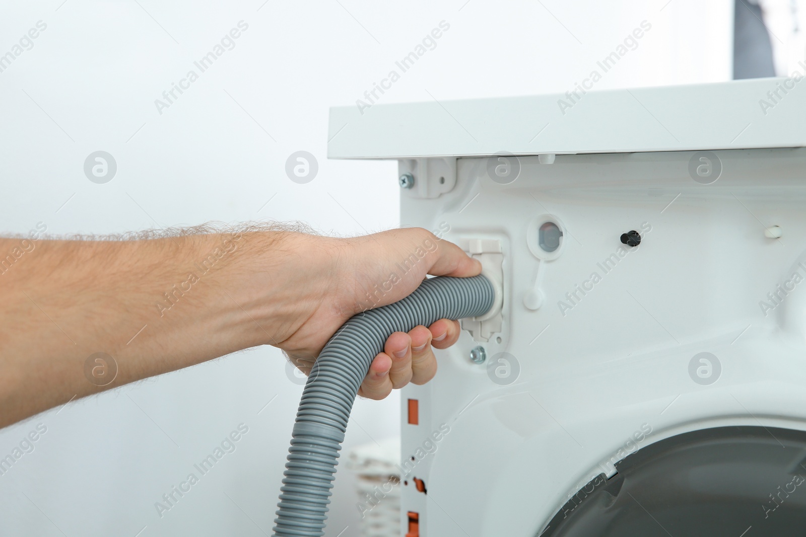 Photo of Young plumber fixing washing machine in bathroom, closeup