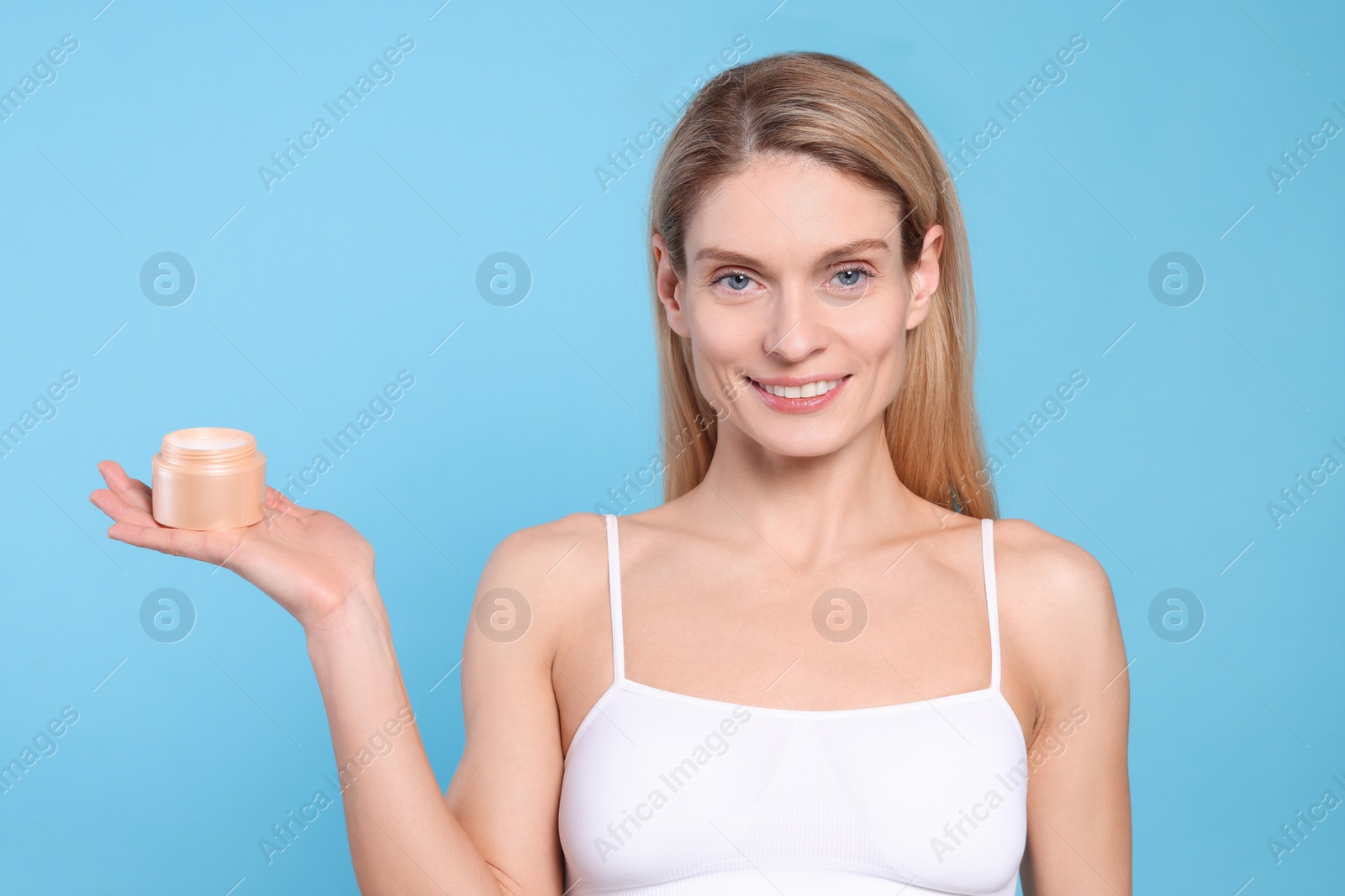Photo of Woman with jar of body cream on light blue background