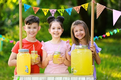 Photo of Cute little children at lemonade stand in park. Summer refreshing natural drink