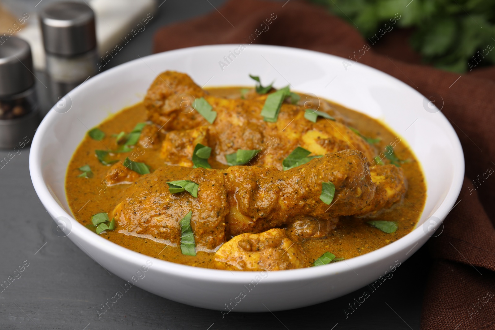 Photo of Delicious chicken with curry sauce on grey wooden table, closeup