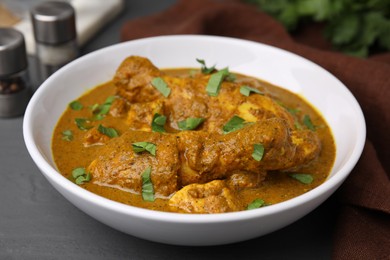 Photo of Delicious chicken with curry sauce on grey wooden table, closeup