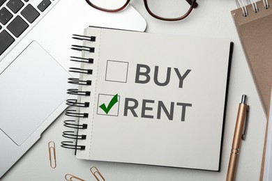 Image of Buy or rent - choice concept. Flat lay composition with notebook on white table