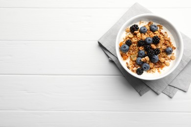 Bowl of healthy muesli served with berries on white wooden table, top view. Space for text