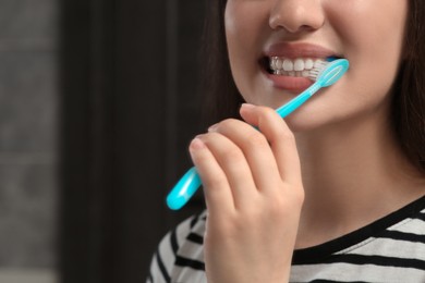 Photo of Woman brushing her teeth with plastic toothbrush in bathroom, closeup